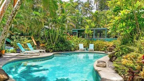 A swimming pool surrounded by lush greenery, with lounge chairs and a building in the background. - Private Hot Tub + Pool Access + AC - Star Lookout (Haiku)