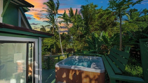 A hot tub on a deck with a view of palm trees and a sunset. - Private Hot Tub + Pool Access + AC - Star Lookout (Haiku)