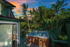 Jacuzzi en una terraza con vistas a palmeras y al atardecer.