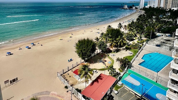 A beach with a pool area, palm trees, and a view of the ocean. - Flash Sale!!!  Newly Renovated Oceanview Property in Isla Verde #2! (Carolina)