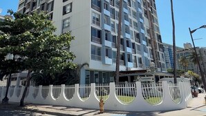 A high-rise building with multiple balconies, a white fence with circular cutouts, and palm trees. - Flash Sale!!!  Newly Renovated Oceanview Property in Isla Verde #2! (Carolina)