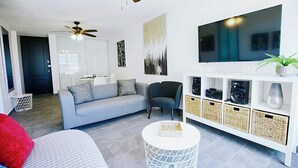 A modern living room with a grey sofa, a white coffee table, and a TV mounted on the wall. - Flash Sale!!!  Newly Renovated Oceanview Property in Isla Verde #2! (Carolina)