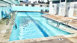 A swimming pool with blue water, surrounded by lounge chairs and a building with a sign that reads "WBC HOTEL". - Flash Sale!!!  Newly Renovated Oceanview Property in Isla Verde #2! (Carolina)