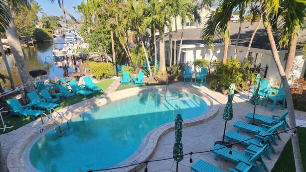 A pool area with two swimming pools, lounge chairs, and umbrellas. - King One Bedroom Overlooking the Pool (Naples)