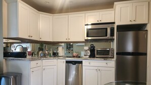 A modern kitchen with white cabinets, stainless steel appliances, and a dishwasher. - King One Bedroom Overlooking the Pool (Naples)