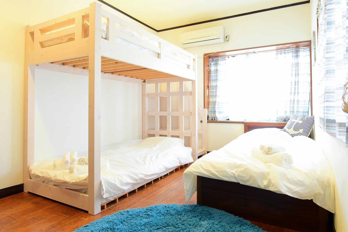 Una habitación con dos literas, una ventana con cortinas y una alfombra azul.