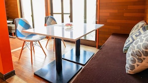 Una habitación moderna con una mesa de vidrio, dos sillas, un sofá y ventanas amplias.