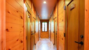 Un pasillo de madera con puertas a ambos lados, que conduce a una habitación con una ventana al final.