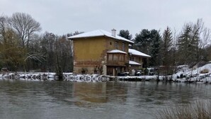 Paisagem coberta de neve com uma casa à beira de um lago.