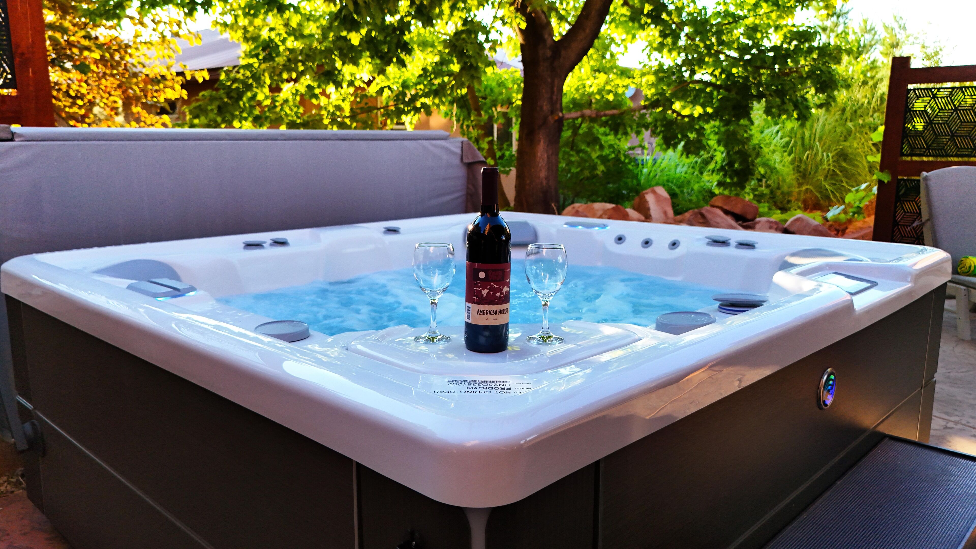 Una vasca idromassaggio con una bottiglia di vino e due bicchieri.