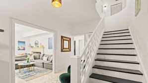 A staircase leading to a second floor, a living room with a sofa, a coffee table, and a green ottoman. - Villa Diamond in South Beach (Miami Beach)