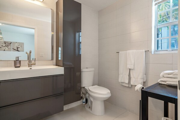 Ein modernes Badezimmer mit Toilette, Waschbecken und Fenster.