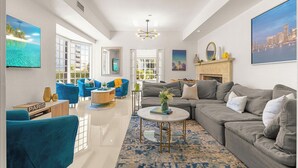 A modern living room with a grey sofa, blue armchairs, a coffee table, and a fireplace. - Villa Diamond in South Beach (Miami Beach)