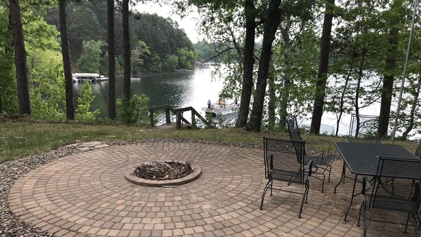 A circular brick patio with a fire pit, metal chairs, and a table. - Beautiful Pristine O'brien Lake Home in Crosslake MN, Sleeps 10 (Crosslake)