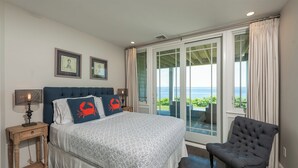 A bedroom with a large bed, two nightstands, a chair, and a view of the sea through large windows. - Exclusive Oceanfront Retreat with Endless Atlantic Views (York Beach)