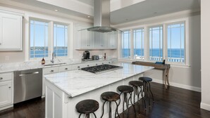 A modern kitchen with a large island, bar stools, and a view of the ocean. - Exclusive Oceanfront Retreat with Endless Atlantic Views (York Beach)