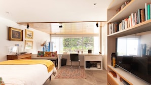 Een moderne slaapkamer met een bed, bureau en televisie.