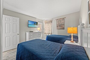 A hotel room with two beds, a television, a dresser, and a window with curtains. - Modern and Clean Condo, Indoor and Outdoor Pools | Waterpointe II - 302 (North Myrtle Beach)