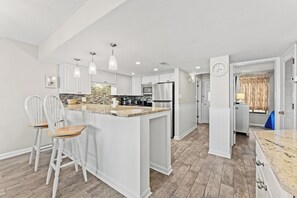 A modern kitchen with white cabinetry, a granite countertop, and pendant lighting.