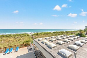 A rooftop terrace with sun loungers, a view of the beach, and a clear sky. - Modern and Clean Condo, Indoor and Outdoor Pools | Waterpointe II - 302 (North Myrtle Beach)