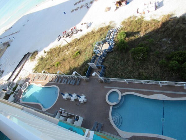 Un espace piscine comprenant plusieurs piscines, des chaises longues et une terrasse avec des escaliers menant à une zone de plage.