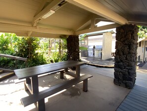 Relax in a serene outdoor space surrounded by lush greenery, featuring a bench and grill area.