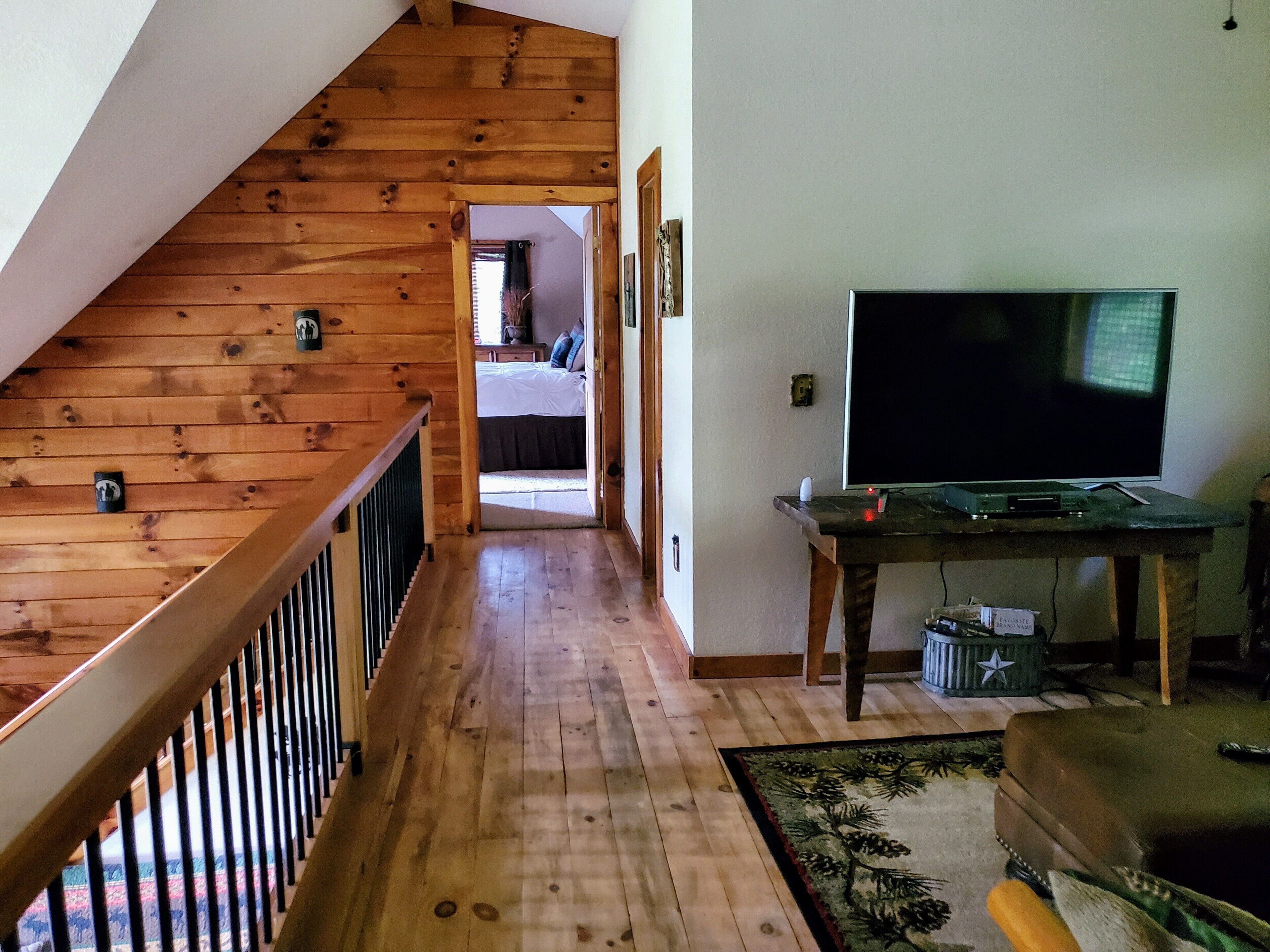 A wooden staircase leading to a bedroom with a TV and a small table.