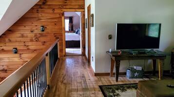 A wooden staircase leading to a bedroom with a TV and a small table.