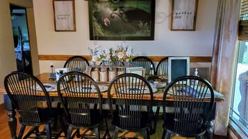 A dining area with a wooden table, black chairs, and framed artwork on the walls.