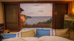 A bedroom with a bed, pillows, and a view of the sea through large windows. - The Beach is Calling!  Book November & December NOW! (Zihuatanejo)