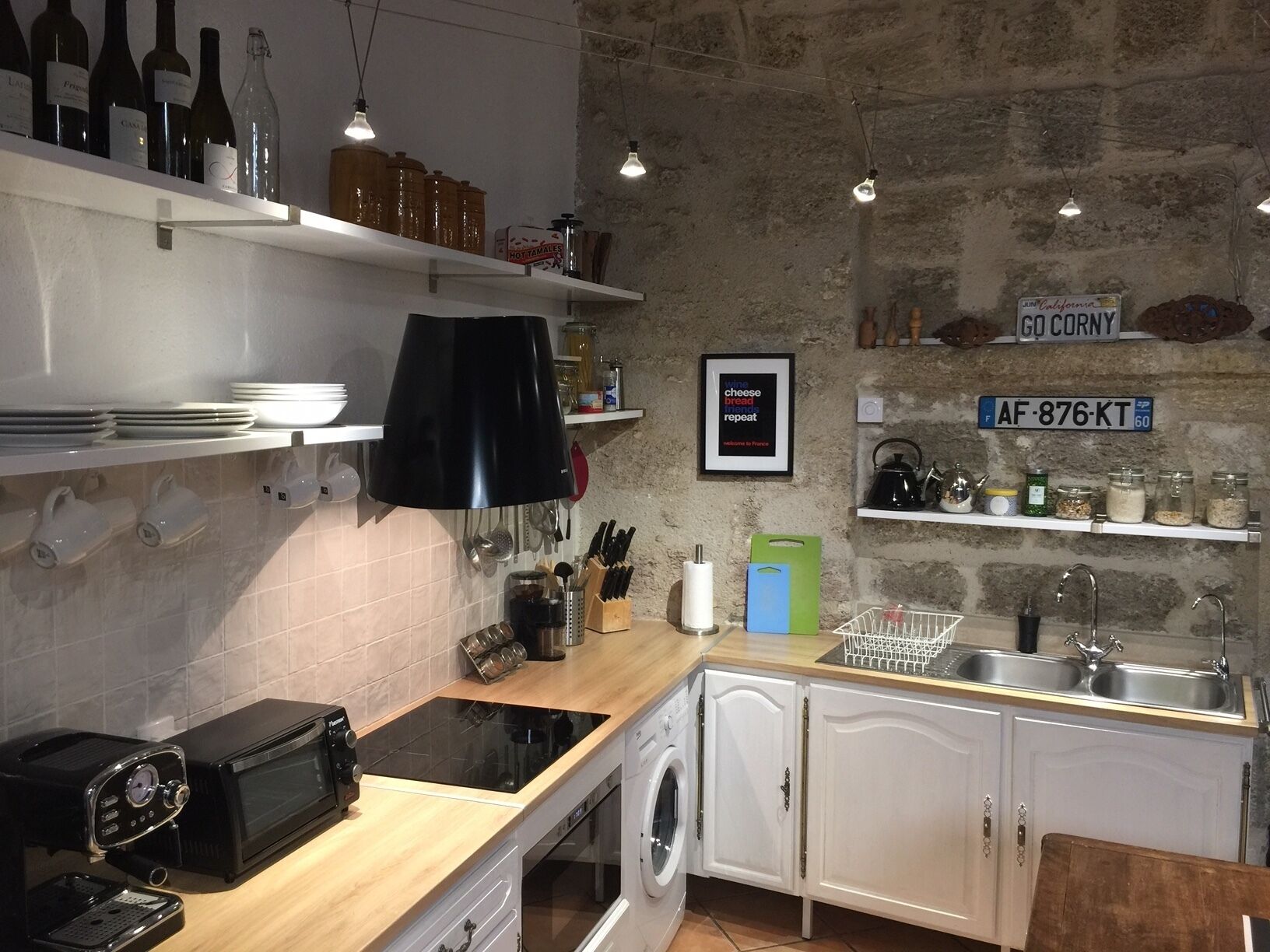 A kitchen with white cabinets, a black countertop, a microwave, a stove, and various kitchen utensils.