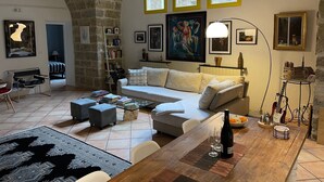 Un salon chaleureux avec un plafond en pierre, un canapé blanc, une table basse et une bibliothèque.