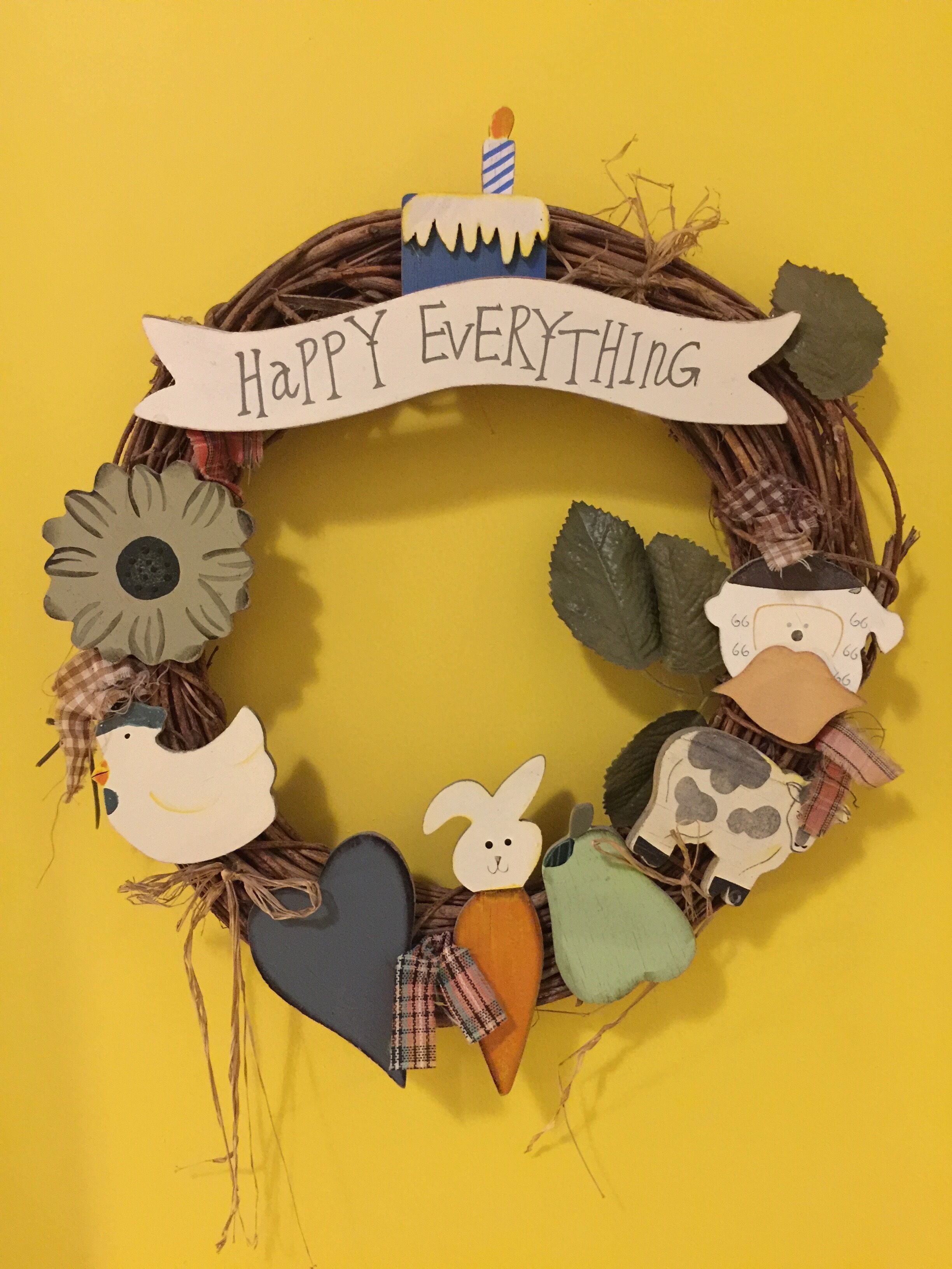 A decorative wreath with a "Happy Everything" banner, featuring various animal and flower cutouts.