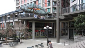 A multi-story building with outdoor seating and a covered area.