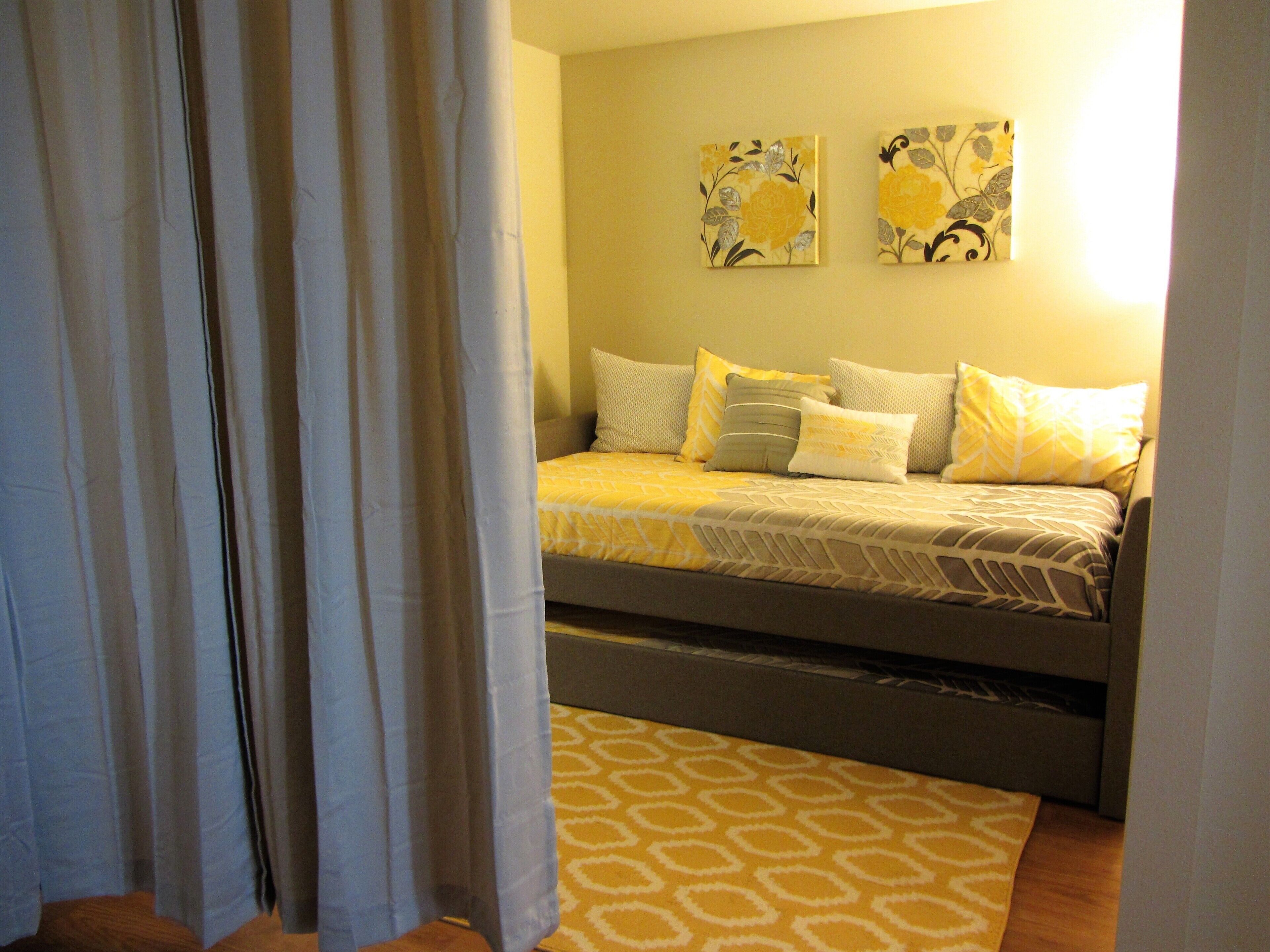 A bedroom with a bed, pillows, and a patterned rug.
