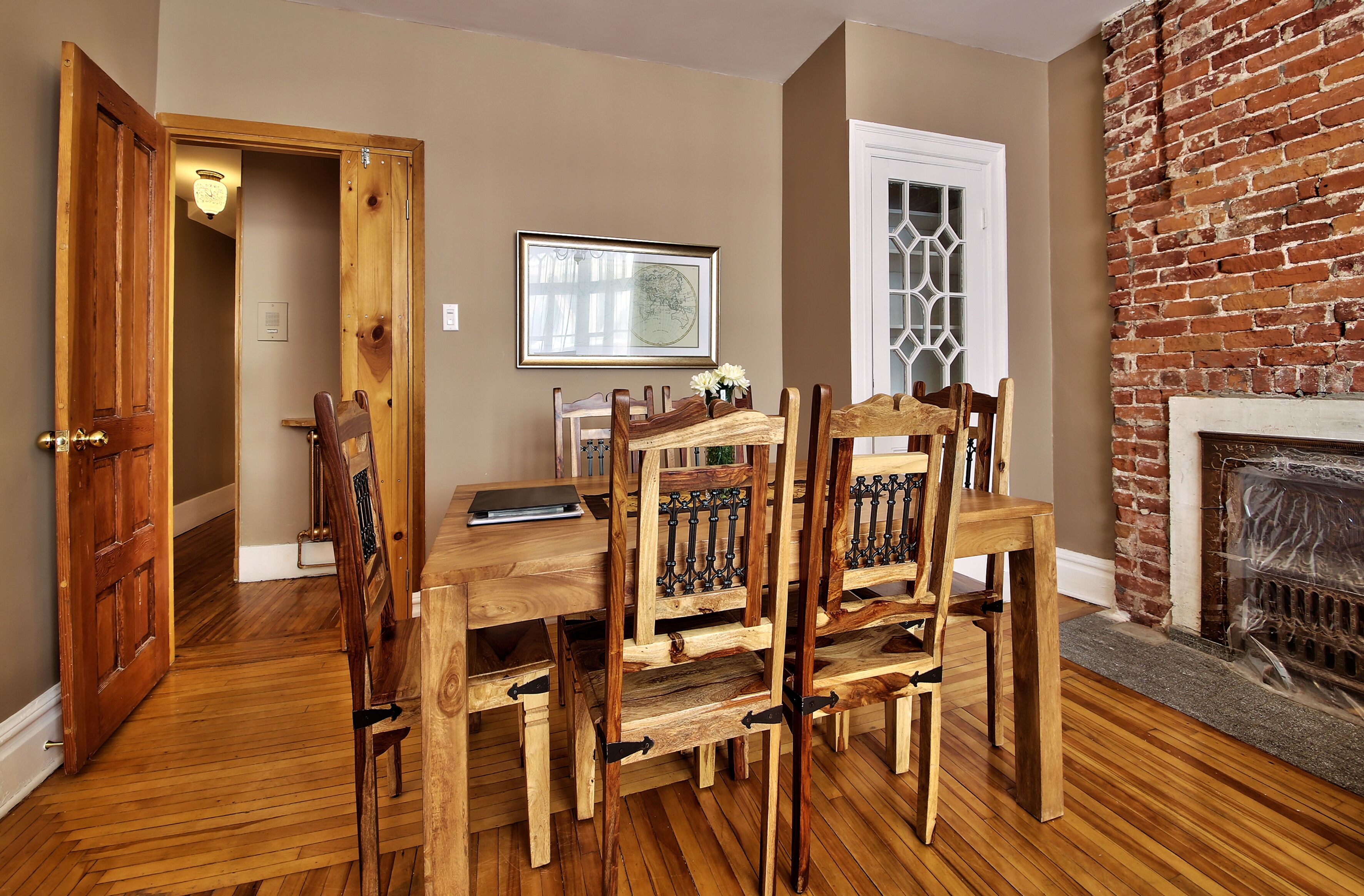 A dining area with a wooden table and chairs, a fireplace, and a door leading to another room.