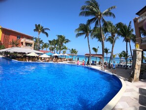 Relax by the pool surrounded by palm trees and lounge chairs.