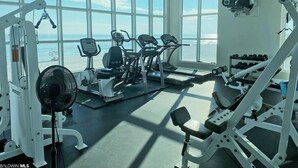 Un gimnasio con máquinas de cardio, equipo de levantamiento de pesas y un ventilador grande.