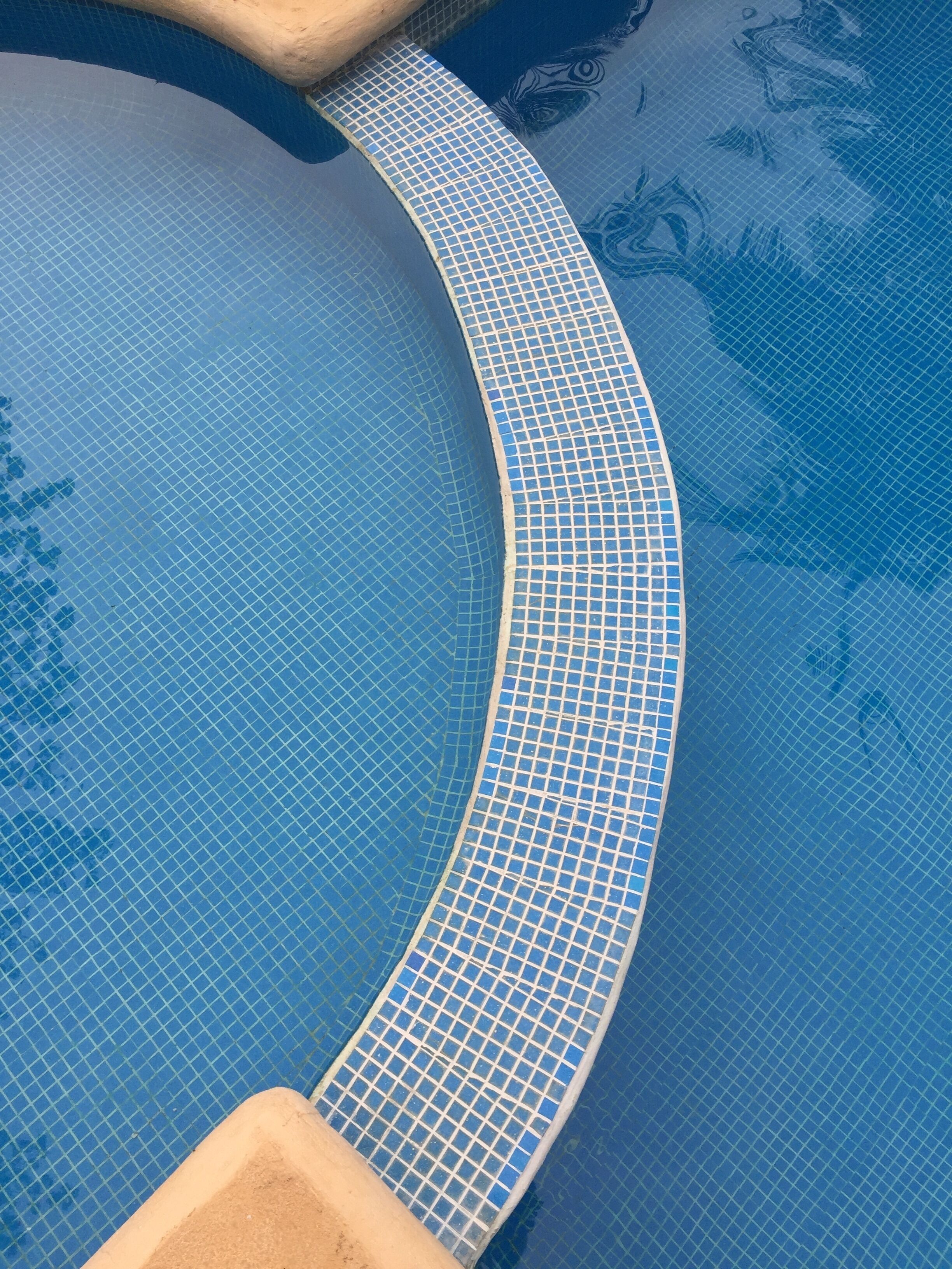 A curved pool edge with a tiled pattern.
