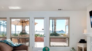 A living room with a sofa, a coffee table with a globe, and large windows offering a view of palm trees and a distant bridge.