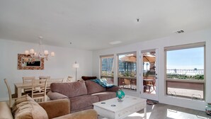 A spacious living room with a large window, a dining area, and a cozy seating arrangement.
