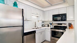 A modern kitchen with white cabinets, stainless steel appliances, and a granite countertop.