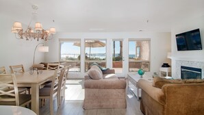 A spacious living room with a wooden dining table, beige sofa, and a fireplace.