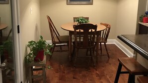 Un coin repas avec une table et des chaises en bois, un lustre et un tableau encadré au mur.