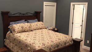 Une chambre à coucher avec un lit, un ventilateur de plafond, une table de chevet et une porte.