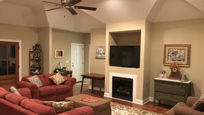 Un salon doté d’une cheminée, d’un téléviseur fixé au-dessus et d’un ventilateur de plafond.