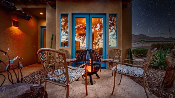 Un patio exterior con una chimenea, cuatro sillas y una mesa.
