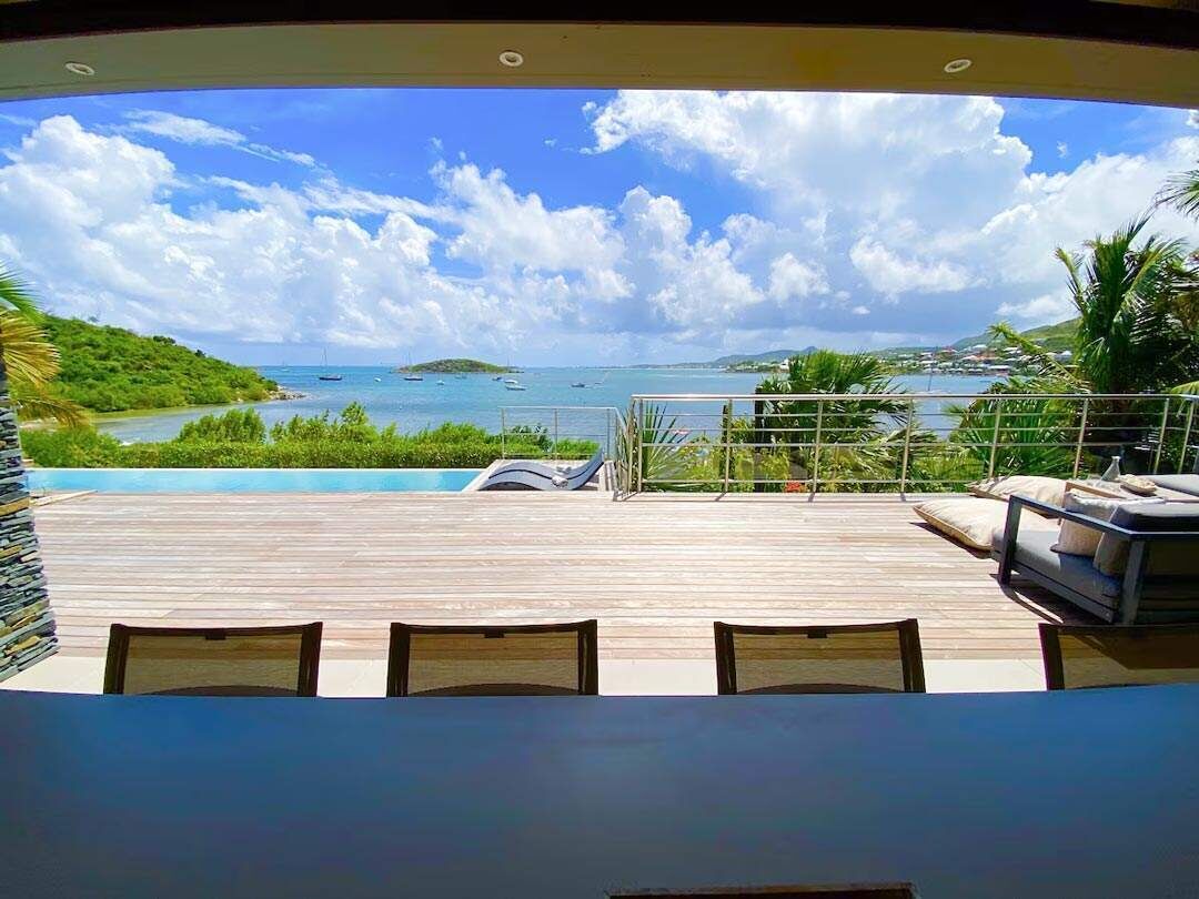Une terrasse avec vue sur la mer, une piscine et un espace détente.