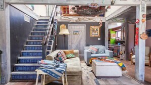 Ein mehrstöckiger Wohnbereich mit Treppe, Sofa, Sessel und kleinem Tisch.