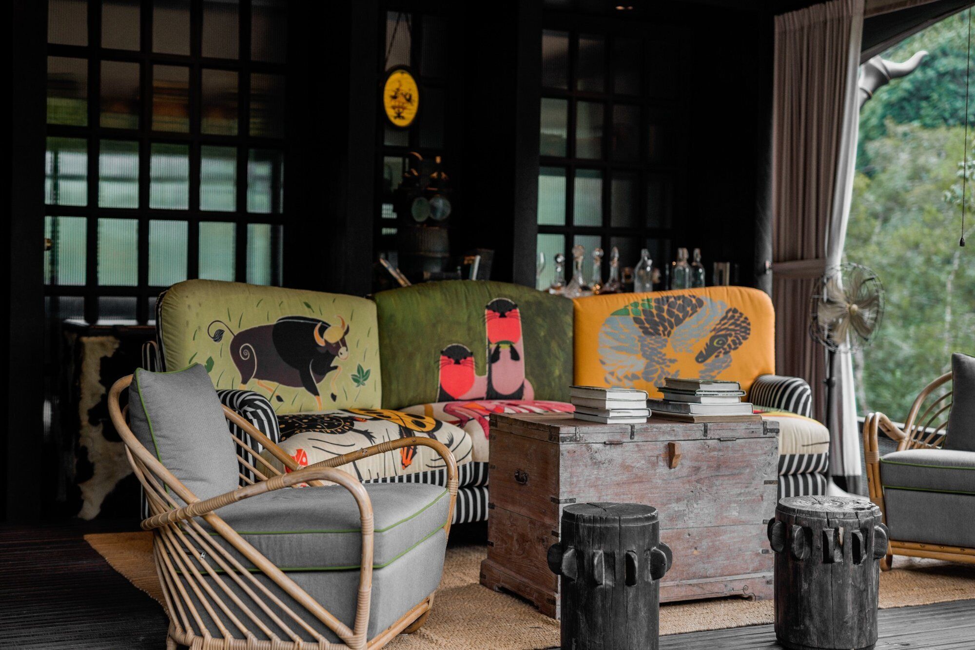 A cozy room with a sofa, chairs, a wooden coffee table, and a window with a view of greenery.